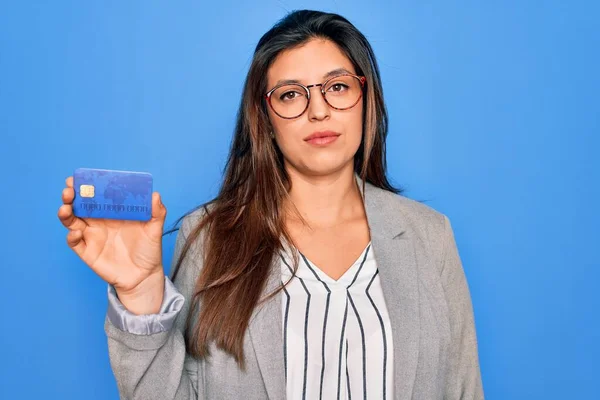 Junge Hispanische Geschäftsfrau Mit Kreditkarte Vor Blauem Hintergrund Und Selbstbewusstem — Stockfoto