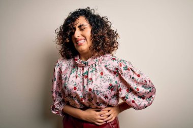 Güzel kıvırcık Arap kadın çiçekli tişört giyer ve midesi bulanan, acı verici bir hastalık yüzünden el üstünde beyaz arka plan üzerinde dikilir. Ache kavramı.