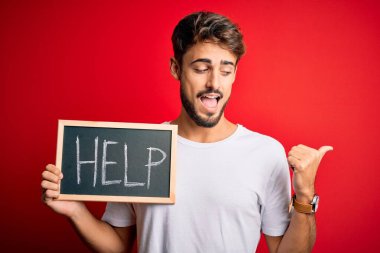 Siyah tahtayı tutmakta zorlanan genç adam kırmızı fırın üzerinden yardım mesajı gönderiyor ve gülümseyen bir gülümsemeyle baş parmağını yana kaldırıyor.