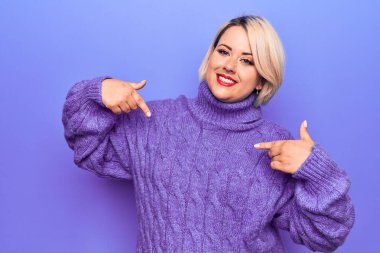 Güzel sarışın ve cüsseli bir kadın mor arka planda balıkçı yaka kazak giyiyor. Kendine güler yüzlü, gururlu ve mutlu birini işaret ediyor..