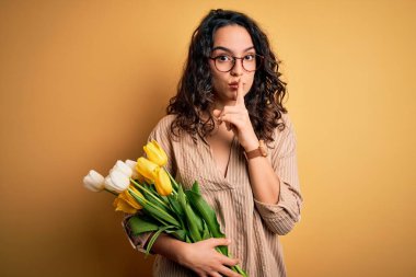 Sarı lale buketi tutan kıvırcık saçlı, genç ve romantik bir kadın sessiz olmak istiyor. Sessizlik ve gizli konsept.