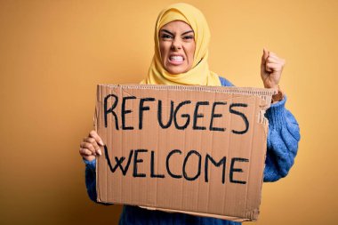 İslami başörtüsü takan güzel bir Arap kadını mültecilerle bayrak tutuyor. Sinirli ve hayal kırıklığına uğramış bir mesaj. Öfkeyle bağırıyor, çıldırıyor ve el kaldırarak bağırıyor.