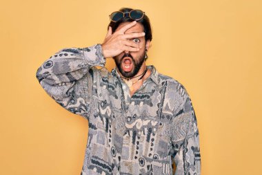 Yakışıklı İspanyol bohem bir adam hippi tarzı giyiniyor ve güneş gözlüğü takıyor. Şok olmuş bir şekilde yüzünü ve gözlerini kapıyor. Utanmış bir ifadeyle parmaklarının arasından bakıyor..