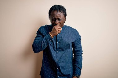 Beyaz arka plan üzerinde dikilen ve soğuk algınlığı veya bronşitin belirtisi olarak öksüren Afro-Amerikan genç adam. Sağlık hizmeti kavramı.