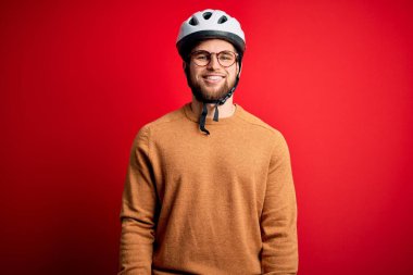 Sakallı, mavi gözlü, bisiklet kaskı takan ve yüzünde mutlu ve havalı bir gülümseme olan genç sarışın bisikletçi. Şanslı kişi..