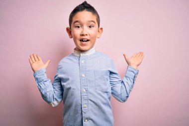 Pembe izole edilmiş arka planda duran zarif tişörtlü küçük çocuk çılgın ve başarıyı kollarını kaldırıp heyecanla haykırarak kutluyor. Kazanan konsept