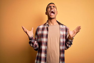 Sarı arka planda dikilen rahat gömlekli genç ve yakışıklı Afro-Amerikalı adam başarıyı kollarını kaldırmış ve gözleri kapalı heyecanla haykırarak kutluyor. Kazanan konsept