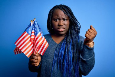 Amerika Birleşik Devletleri bayrakları taşıyan genç, vatansever Afro-Amerikan artı cüsseli kadın öfkeyle bağırıyor, deliriyor ve öfkeyle bağırıyor.