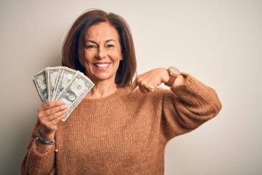 Orta yaşlı esmer bir kadın, elinde bir dolarlık banknotlarla izole edilmiş arka planda, kendini işaret eden sürpriz yüzlü bir kadınla.