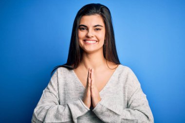 Genç, güzel, esmer, sıradan bir kazak giyen, mavi arka planda dua eden, ellerini birleştirip af dileyen, kendinden emin gülümseyen bir kadın..