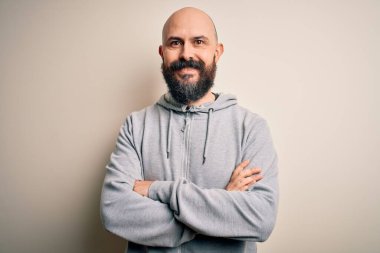 Yakışıklı, sakallı, pembe arka planda duran, kollarını kavuşturup kameraya bakan, kazaklı, kel ve yakışıklı bir adam. Pozitif kişi.