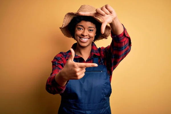 若いアフリカ系アメリカ人のアフロ農家の女性は エプロンと帽子を身に着けている巻き毛の女性は幸せな顔を持つ手や指でフレームを作り笑顔 創造性と写真の概念 — ストック写真