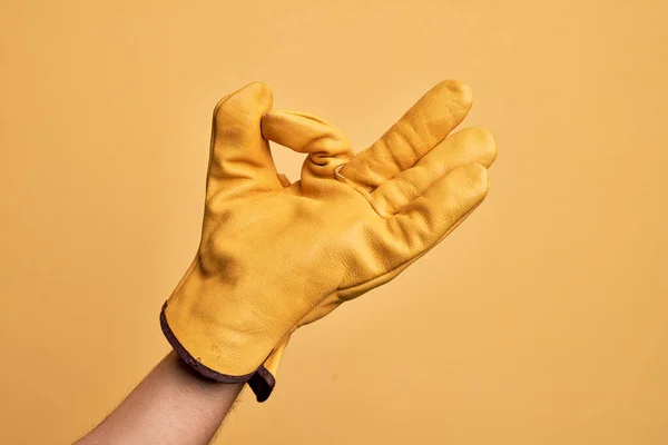 带园艺师手套的高加索年轻人的手在孤立的黄色背景上做一个表示赞许的表情 用手指做一个好的符号 — 图库照片