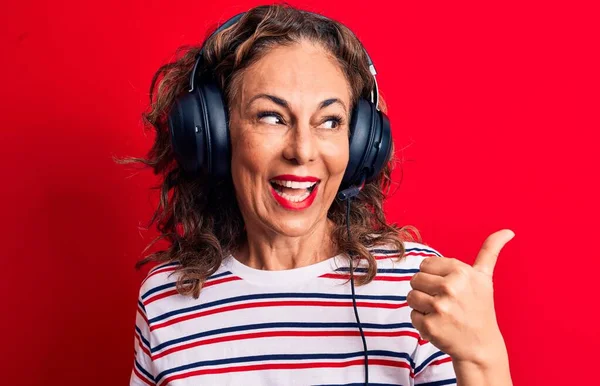 中世ブルネットゲーマー女性ゲームをプレイするビデオゲームを使用してヘッドフォンとマイク指差す親指アップへザサイド笑顔幸せとともにオープン口 — ストック写真