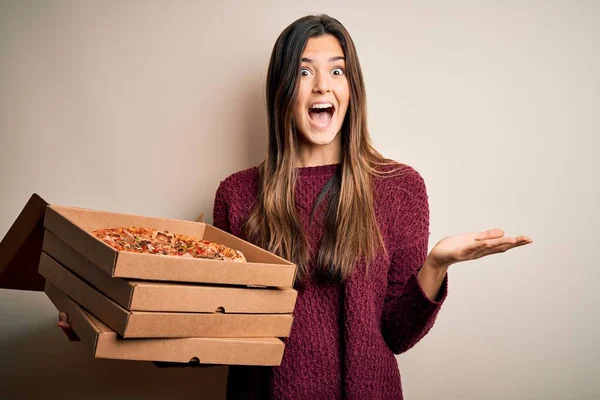 若いです美しいです女の子保持デリバリーボックスでイタリアのピザは白い背景の上に立って非常に幸せと興奮 受賞式は大きな笑顔で叫んで勝利を祝いますと手を上げ — ストック写真