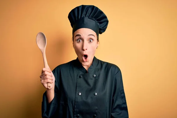 年轻美丽的厨师女士身穿炊事服 头戴木勺帽 吓得满脸诧异 吓得面无血色 — 图库照片