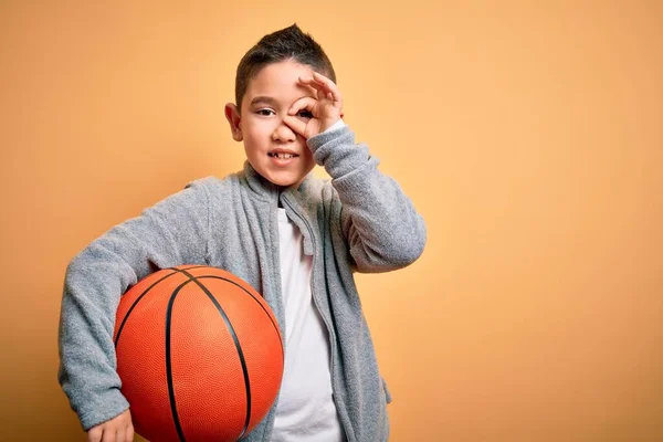 Mladý Chlapec Kluk Hraje Basketbalovým Míčem Přes Izolované Žluté Pozadí — Stock fotografie