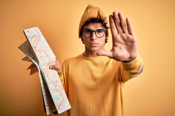 Młody Turysta Trzymający Mapę Okularach Czapce Odizolowanym Żółtym Tle Otwartą — Zdjęcie stockowe