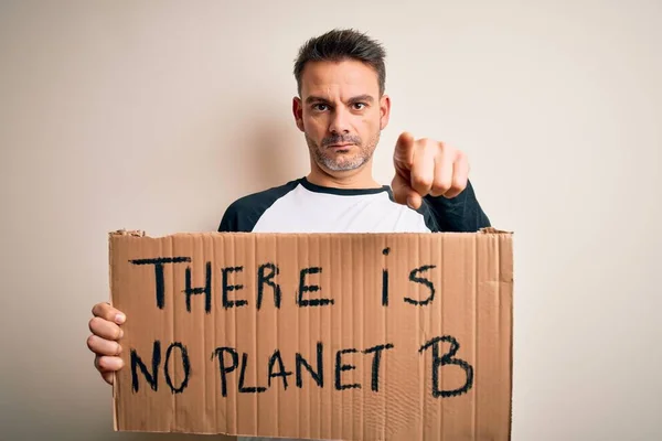 Young handsome man asking for environment holding banner with planet message pointing with finger to the camera and to you, hand sign, positive and confident gesture from the front