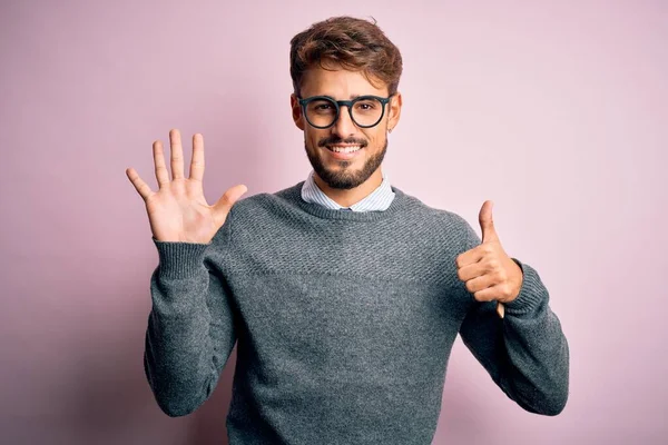 Sakallı Gözlüklü Süveterli Genç Adam Pembe Arka Planda Dikiliyor Parmaklarıyla — Stok fotoğraf