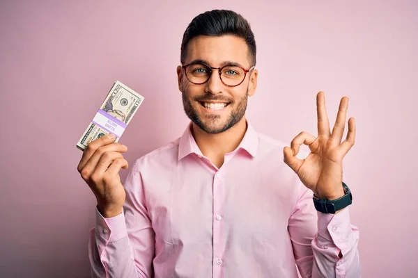 Молодий Бізнесмен Тримає Купу Банкнот Доларів Над Рожевим Ізольованим Тлом — стокове фото