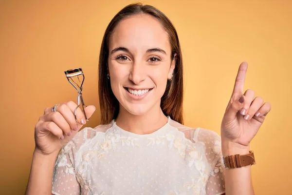 Joven Hermosa Mujer Usando Rizador Pestañas Pie Sobre Fondo Amarillo —  Fotos de Stock