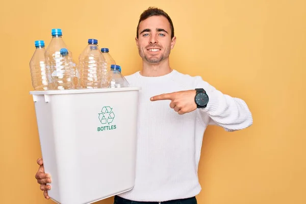 青い目の若いですハンサムな男リサイクル保持Wastebasketとともにプラスチックボトル笑顔幸せなポインティングで手と指 — ストック写真