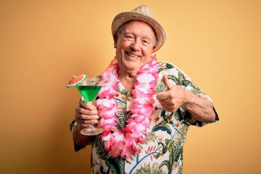 Beyaz saçlı, yaz şapkası takan ve Hawaii zambağı içen mutlu bir kokteyl içen yaşlı bir adam.