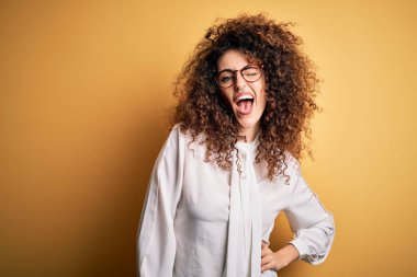 Kıvırcık saçlı, piercing takan, gözlüklü, seksi bir ifadeyle kameraya bakan, neşeli ve mutlu yüzlü güzel esmer kadın..