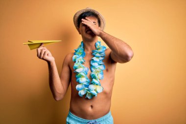 Tatilde mayo giyen genç bir turist ve elinde kağıt uçakla gezen Hawaii çiçekleri utanç ve şaşkınlık dolu, sinirli ve hayal kırıklığına uğramış bir halde. Hata için korku ve üzüntü.