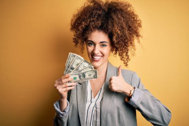 Kıvırcık saçlı, piercingli, dolarlar tutan güzel bir kadın. Büyük bir gülümsemeyle mutlu.