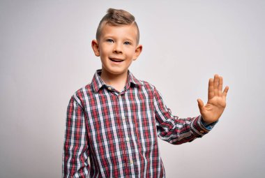 Mavi gözlü, zarif gömlekli küçük beyaz çocuk izole arka planda duruyor ve parmaklarını 5 numarayı gösterirken kendinden emin ve mutlu gülümsüyor..