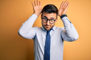 Sarı arka planda duran kravat ve gözlük takan genç yakışıklı iş adamı avuç içi hareketleriyle kuşkucu ve şüpheci görünüyor. Paskalya tavşanı kavramı.