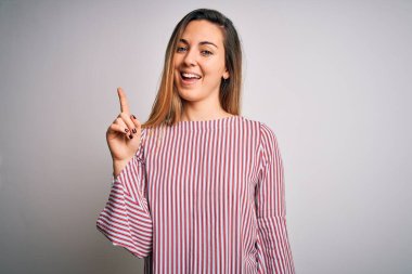 Mavi gözlü, beyaz arka planda ince tişörtlü, genç, güzel sarışın bir kadın. Bir numarayı işaret ediyor, kendinden emin ve mutlu bir şekilde gülümsüyor..