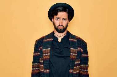 Genç, yakışıklı, bohem, hippi tarzı giyinen ve bohem şapkalı, sıkıntılı, sinirli ve korkmuş bir adam. Üzücü ifade.