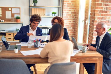 Bir grup iş adamı mutlu ve kendinden emin gülümsüyor. Ofiste birlikte çalışırken gülümseyerek konuşmak..