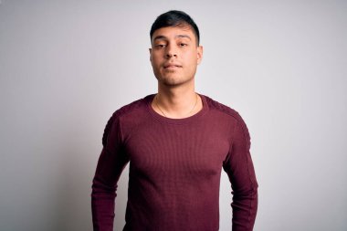 Beyaz izole edilmiş arka plan üzerinde duran gündelik tişört giyen genç, yakışıklı İspanyol adam yüzünde ciddi bir ifadeyle rahatlamış. Basit ve doğal bir şekilde kameraya bakıyorsun..