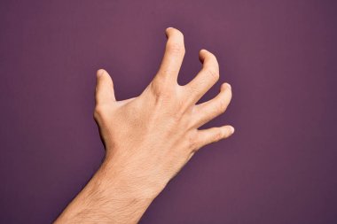İzole edilmiş mor arka planda parmaklarını gösteren beyaz bir gencin eli parmaklarıyla saldırganlaştırıyor ve korkutuyor. Şiddet ve hüsranla.