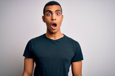 Beyaz arka planda dikilen, korku, şaşkınlık ifadesi, korku ve heyecan dolu yüz ifadesinden korkan, şok olmuş genç ve yakışıklı Afro-Amerikan erkeği..