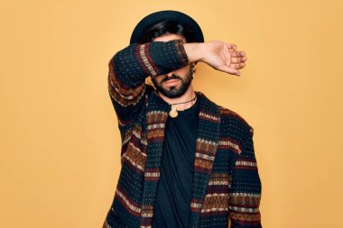 Genç, yakışıklı, bohem, hippi tarzı giyinen ve gözlerini kollarıyla kapatan, ciddi ve üzgün görünen bir adam. Görme, saklama ve reddetme konsepti