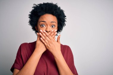 Kıvırcık saçlı, sıradan tişörtlü, ağzı yanlışlıkla ellerle kapatan güzel Afro-Amerikan kadın. Gizli konsept.