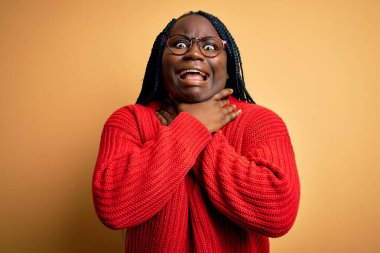 Afrikalı Amerikalı, örgü ören, sarı arka planda rahat süveter giyen ve boğularak ölen iri yarı bir kadın. Sağlık problemi. Boğulma ve intihar konsepti.