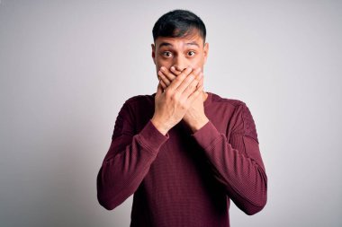 Beyaz izole edilmiş arka planda dikilen gündelik tişört giyen genç, yakışıklı İspanyol adam yanlışlıkla ağızlarını kapatarak şok geçirdi. Gizli konsept.