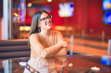 Mutlu ve kendinden emin gülümseyen genç ve güzel bir kadın. Barda gülümseyerek oturmak.