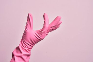 İzole edilmiş pembe arka plan üzerinde temizlik eldiveni olan beyaz bir adamın eli. Görünmez bir şeyi alıp, parmaklarında boşluk gösteren bir nesneyi tutuyor.