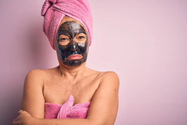 Middle age brunette woman wearing beauty black face mask over isolated pink background shaking and freezing for winter cold with sad and shock expression on face