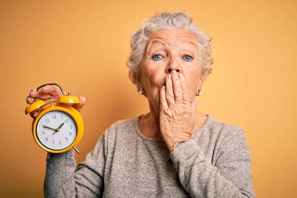 Senior Bela Mulher Segurando Despertador Sobre Isolado Amarelo Fundo Cobrir — Fotografia de Stock