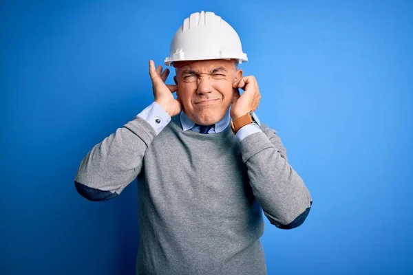 중년의 잘생긴 머리의 기술자는 시끄러운 음악을 짜증나는 표정으로 손가락으로 헬멧을 — 스톡 사진