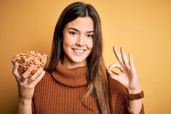 Menina Bonita Nova Segurando Tigela Amendoins Salgados Sobre Fundo Amarelo — Fotografia de Stock