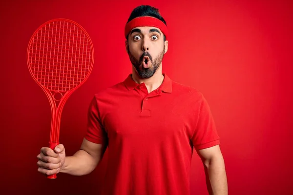 年轻英俊的运动员 留着胡子 用球拍在红色背景下打网球 吓得满脸诧异 吓得面无血色 吓得面无血色 — 图库照片